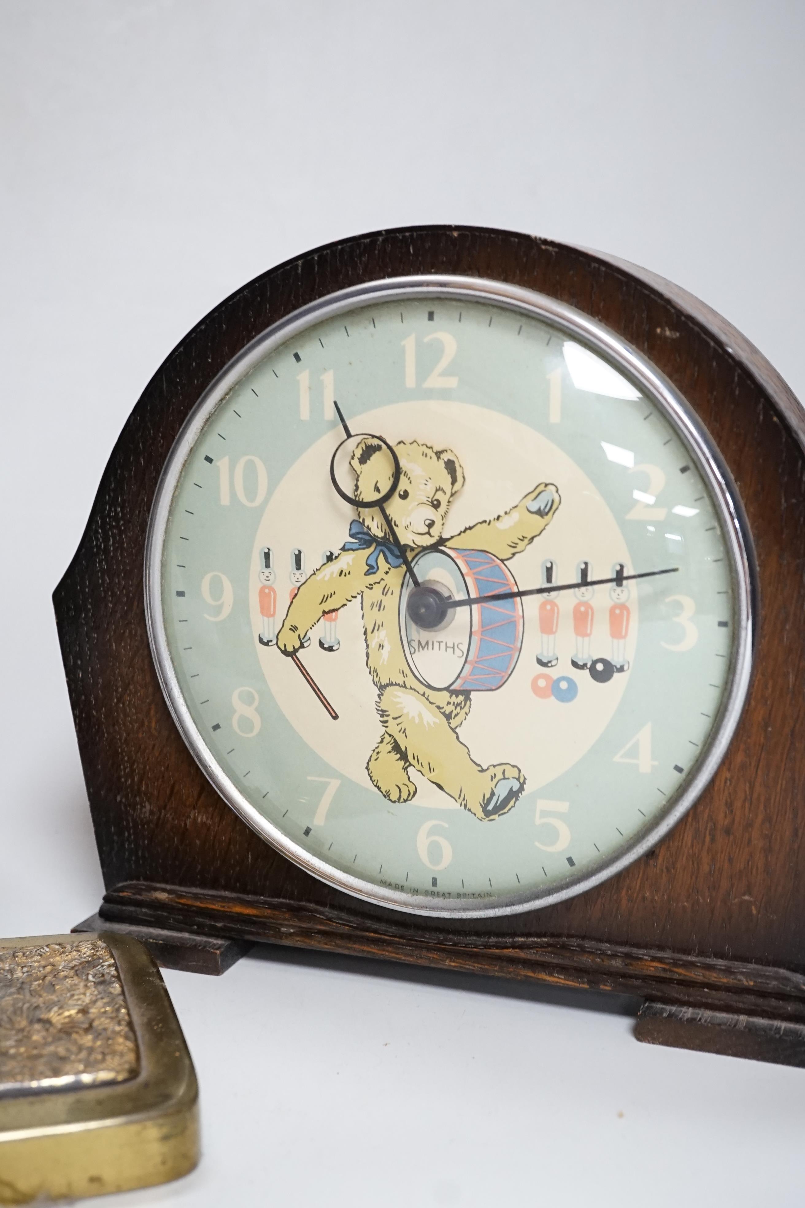 A Smith teddy bear clock, a seated metal bear holding a pocket watch, a metal standing bear with parasol and a German metal bear calendar